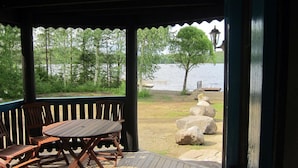 A wooden deck with a table and chairs, overlooking a lake with trees and rocks. - Kiviniemi by Interhome (Tohmajärvi)
