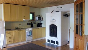 A kitchen with yellow cabinets, a microwave, a stove, and a fireplace. - Kiviniemi by Interhome (Tohmajärvi)