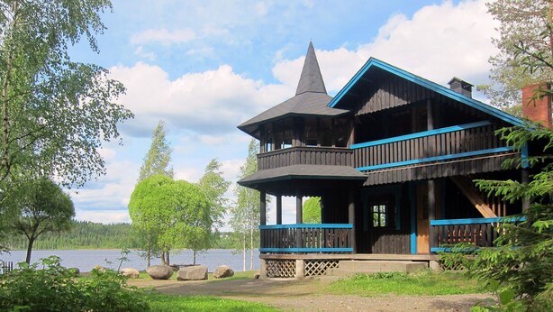 A wooden cabin with a balcony overlooking a lake, surrounded by trees. - Kiviniemi by Interhome (Tohmajärvi)