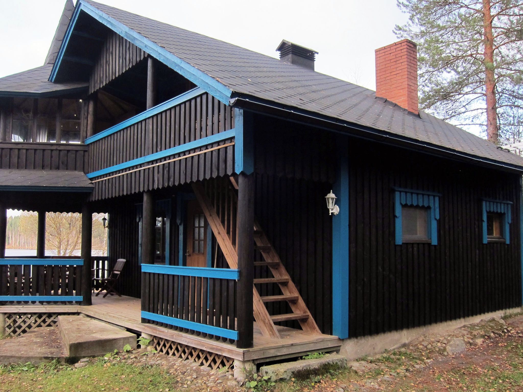 A wooden cabin with a balcony, a staircase, and a chimney.