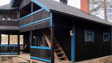 A wooden cabin with a balcony, a staircase, and a chimney.