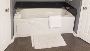 Et badeværelse med et hvidt badekar, en sort bordplade og et hvidt håndklæde.