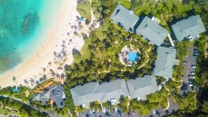 Eine Luftaufnahme eines Resorts mit mehreren Gebäuden, einem Strand und einem Schwimmbad.