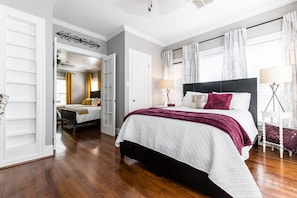 A bedroom with a large bed, a bedside table, a chair, and a wardrobe.