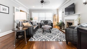 A modern living room with a fireplace, leather sofas, a coffee table, and a patterned rug.
