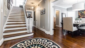 A staircase with a wooden finish, a dining area with a table and chairs, and a hallway with a patterned rug.
