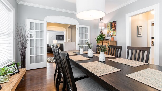 A dining area with a long table, chairs, and a modern pendant light.