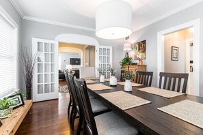 A dining area with a long table, chairs, and a modern pendant light. - The Roux House Offers Luxury, Comfort & Location! (Dallas)