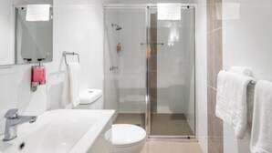 Une salle de bain moderne avec un lavabo blanc, des toilettes et une douche à parois de verre.