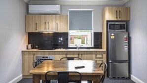 Une cuisine compacte avec des meubles en bois, un four à micro-ondes encastré et un réfrigérateur.