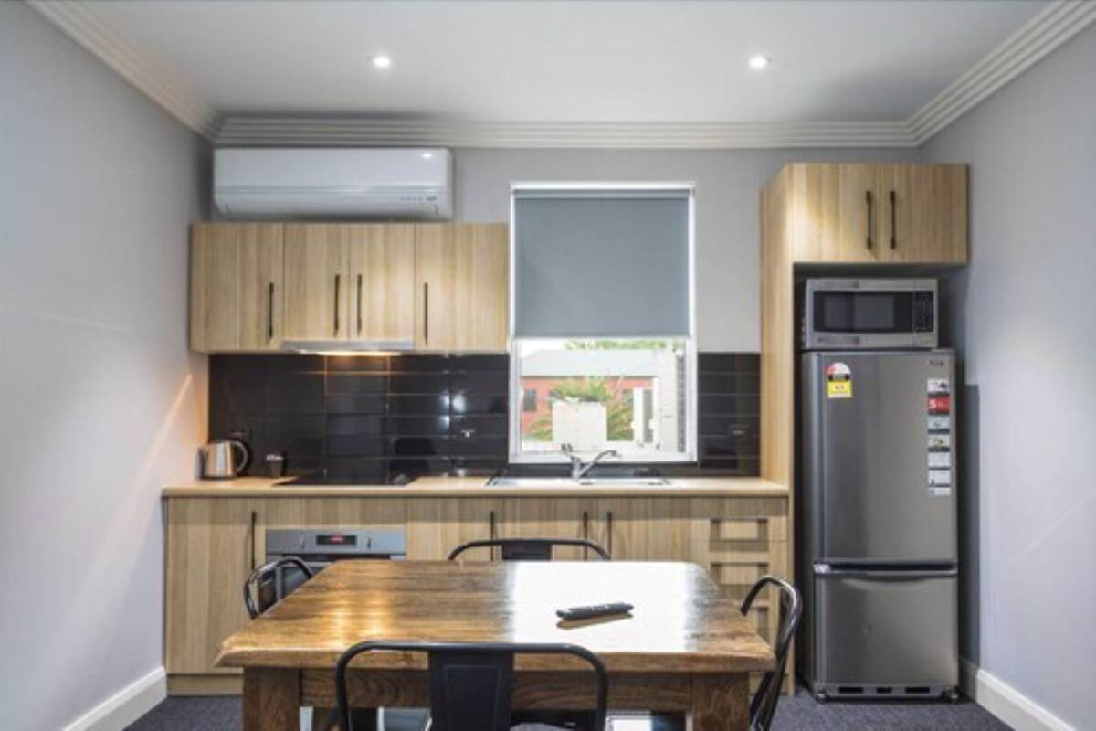 A compact kitchen with wooden cabinets, a built-in microwave, and a refrigerator.