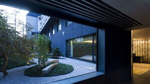 A modern building exterior with large windows, a garden area with gravel and plants, and a geometric wall pattern. - Shizutetsu Hotel Prezio Kyoto-Shijo (Kyoto)