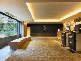 A hotel lobby with a reception desk, seating area, and a wall-mounted decorative piece.