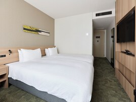 Une chambre d’hôtel avec un grand lit, une table de chevet, un téléviseur à écran plat et une œuvre d’art accrochée au mur.