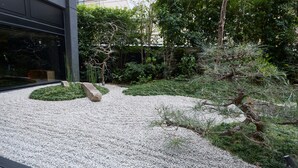 A gravel courtyard with a stone pathway, surrounded by greenery and trees. - Shizutetsu Hotel Prezio Kyoto-Shijo (Kyoto)
