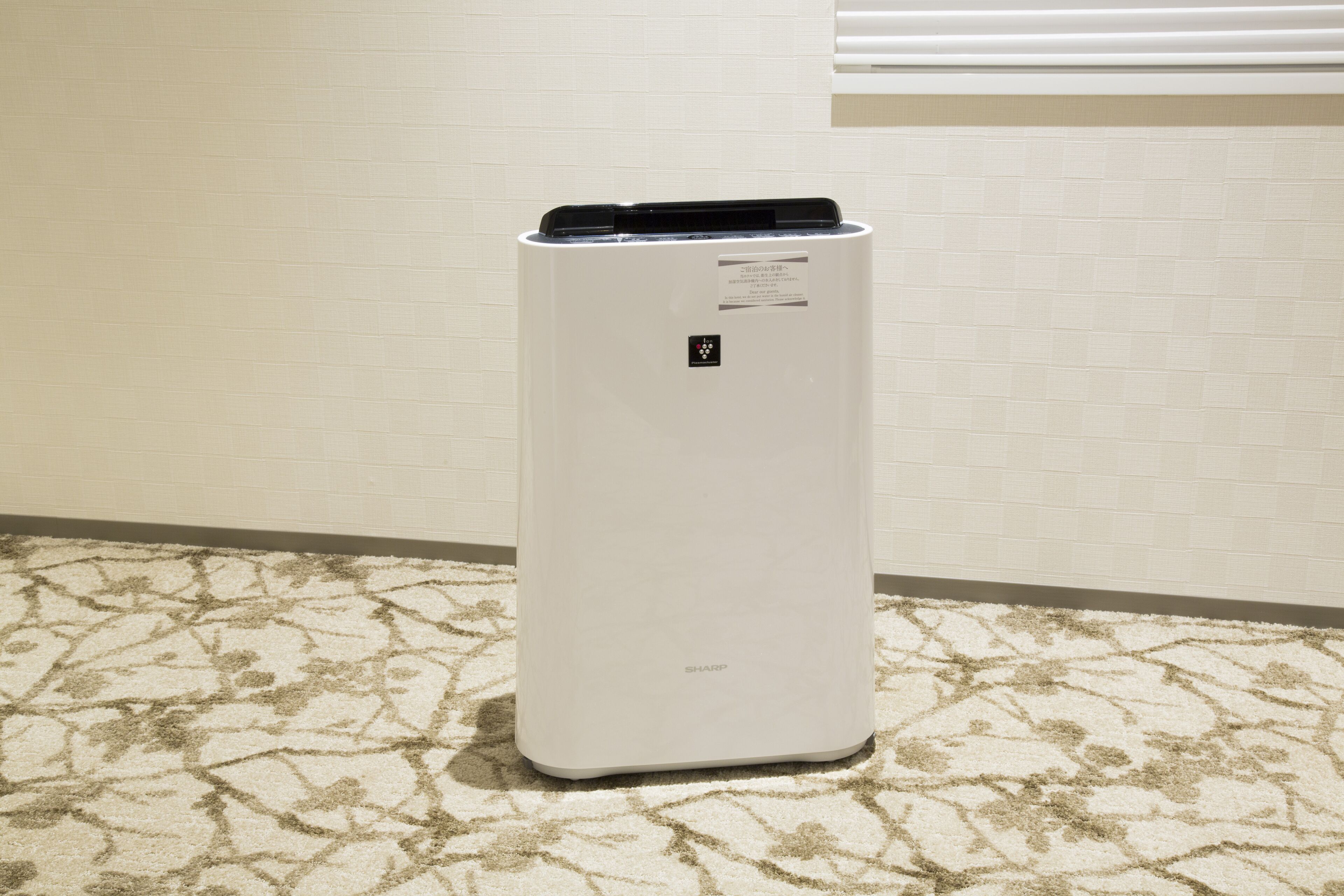 Un equipo de aire acondicionado blanco con un panel de control sobre una alfombra estampada.