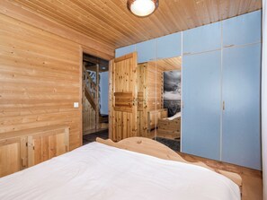 A wooden room with a bed, a wardrobe, and a door leading to a staircase. - Vastaniemi by Interhome (Lapinlahti)