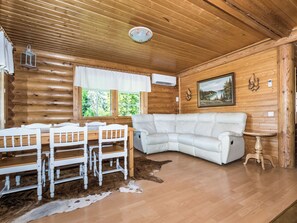 A log cabin interior with a white sofa, dining table, and chairs, a cowhide rug, and a painting on the wall. - Vastaniemi by Interhome (Lapinlahti)