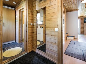 Un intérieur en bois comprenant un sauna, un petit coin salon et une porte visible donnant sur une autre pièce.