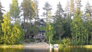 A lakeside cabin with a dock, surrounded by dense forest.