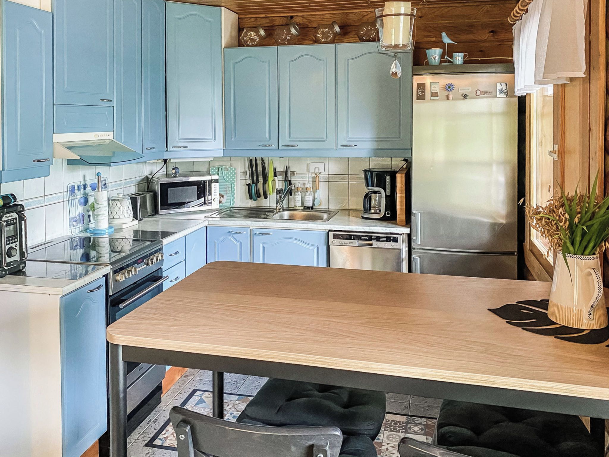 Una cocina con armarios azul claro, una encimera de madera y diversos electrodomésticos, incluyendo un microondas, tostadora y cafetera.