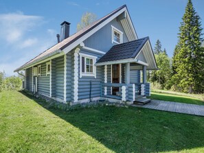 A log cabin with a porch and a chimney, surrounded by a grassy yard and trees. - Vastaniemi by Interhome (Lapinlahti)