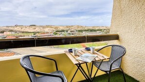 A balcony with two chairs and a table, overlooking a construction site and a hilly landscape. - Trinquart by Interhome (Seignosse)