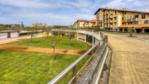 A residential area with a curved pathway, a grassy lawn, and a multi-story building with balconies. - Trinquart by Interhome (Seignosse)