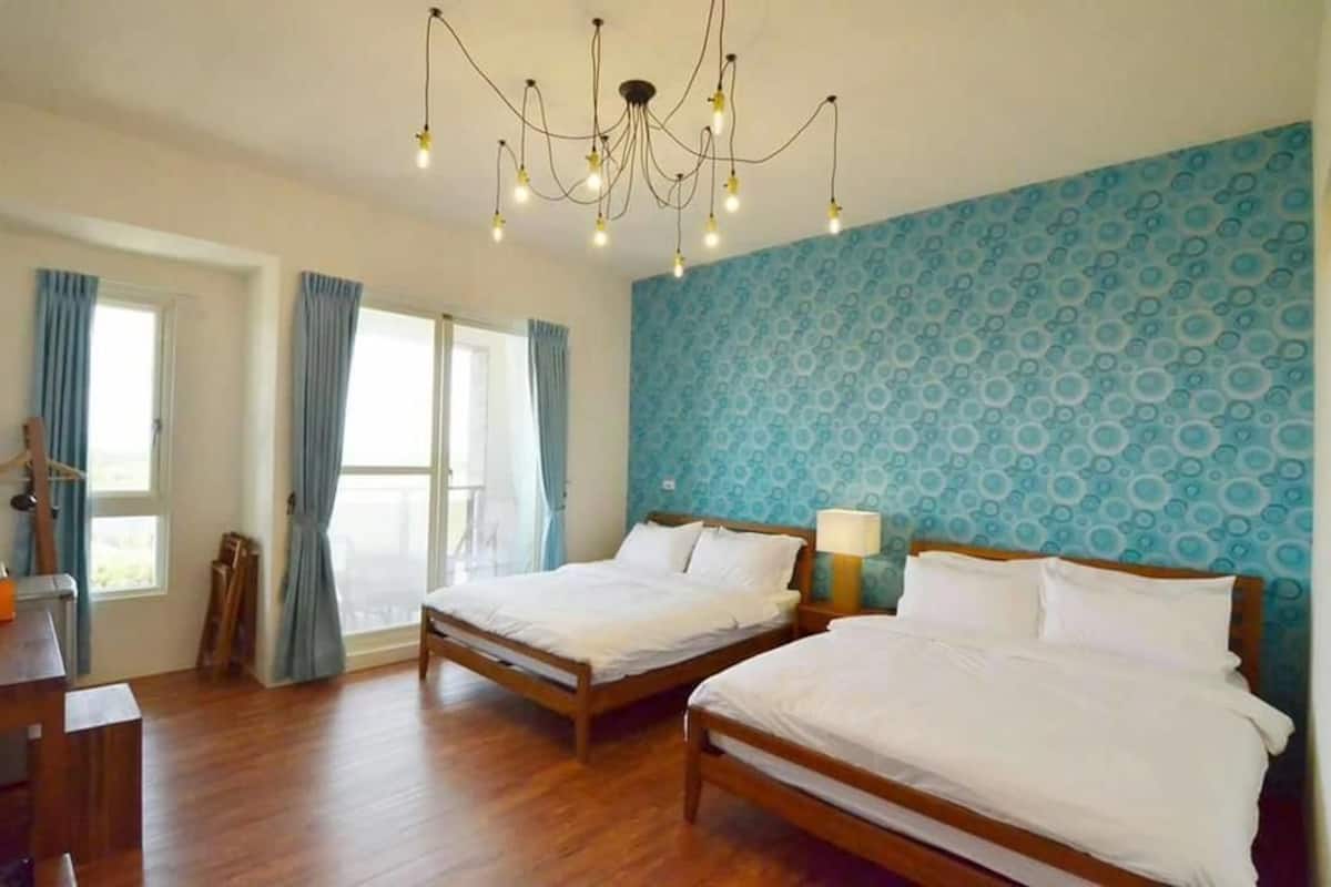Una habitación con dos camas de madera, un candelabro y una pared con estampado azul.