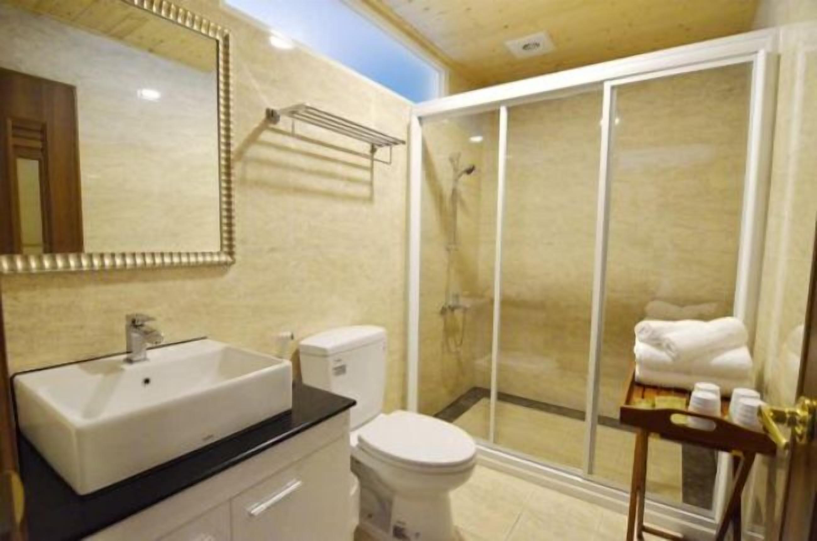 A bathroom with a sink, toilet, and a glass-enclosed shower area.