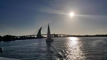 A sailboat on a river with a bridge in the background.