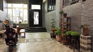 Un grand espace intérieur doté d’un sol carrelé, d’une moto et d’un escalier menant à une porte.
