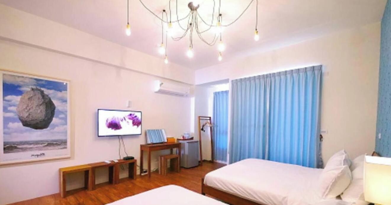 A hotel room with a bed, a desk, a television, and a window with curtains.