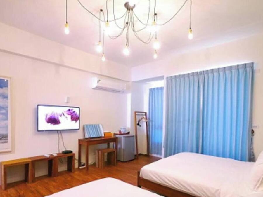 A hotel room with a bed, a desk, a television, and a window with curtains.