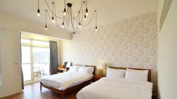 Une chambre d’hôtel avec deux lits, un lustre, un papier peint à motifs et une grande fenêtre.