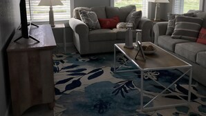 A living room with a sofa, two lamps, a coffee table, and a TV on a stand. - Cottage by the beach ! Short 120 steps to the beach and its beautiful waiting ! (Mexico Beach)