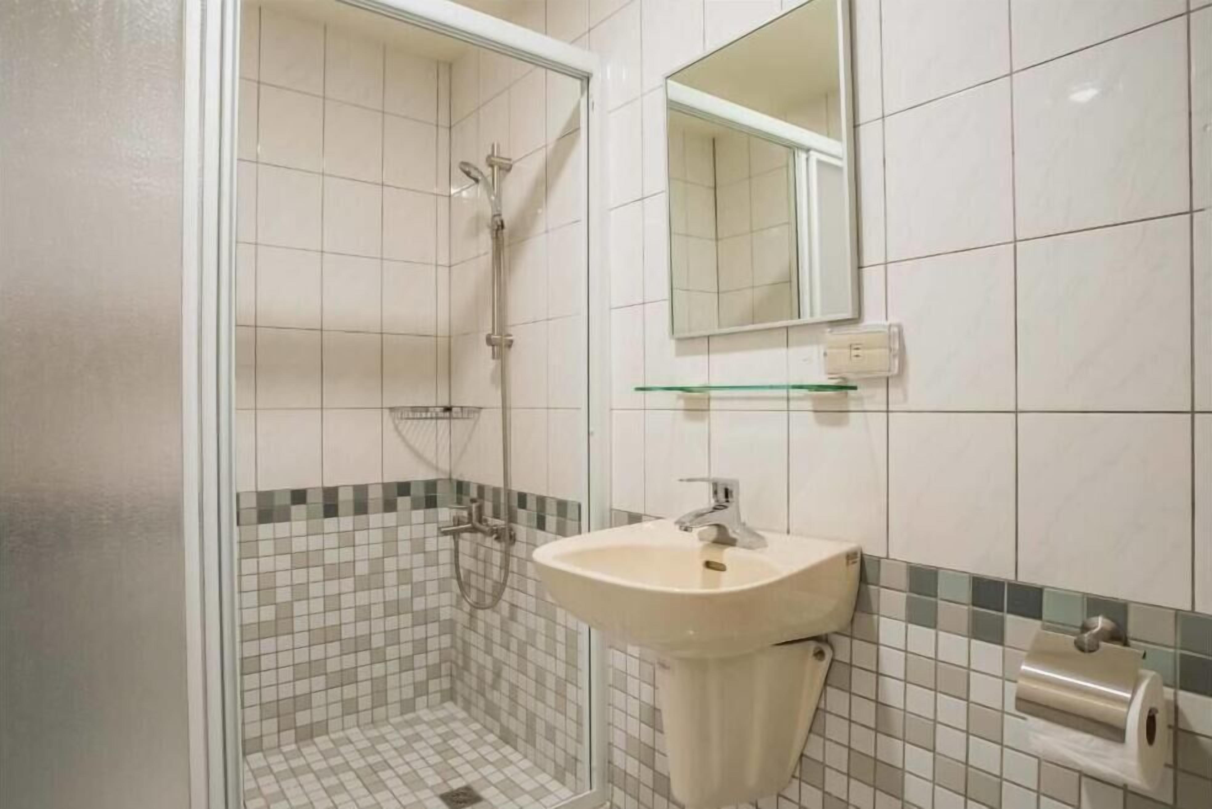 Ein Badezimmer mit Dusche, Waschbecken und Spiegel.