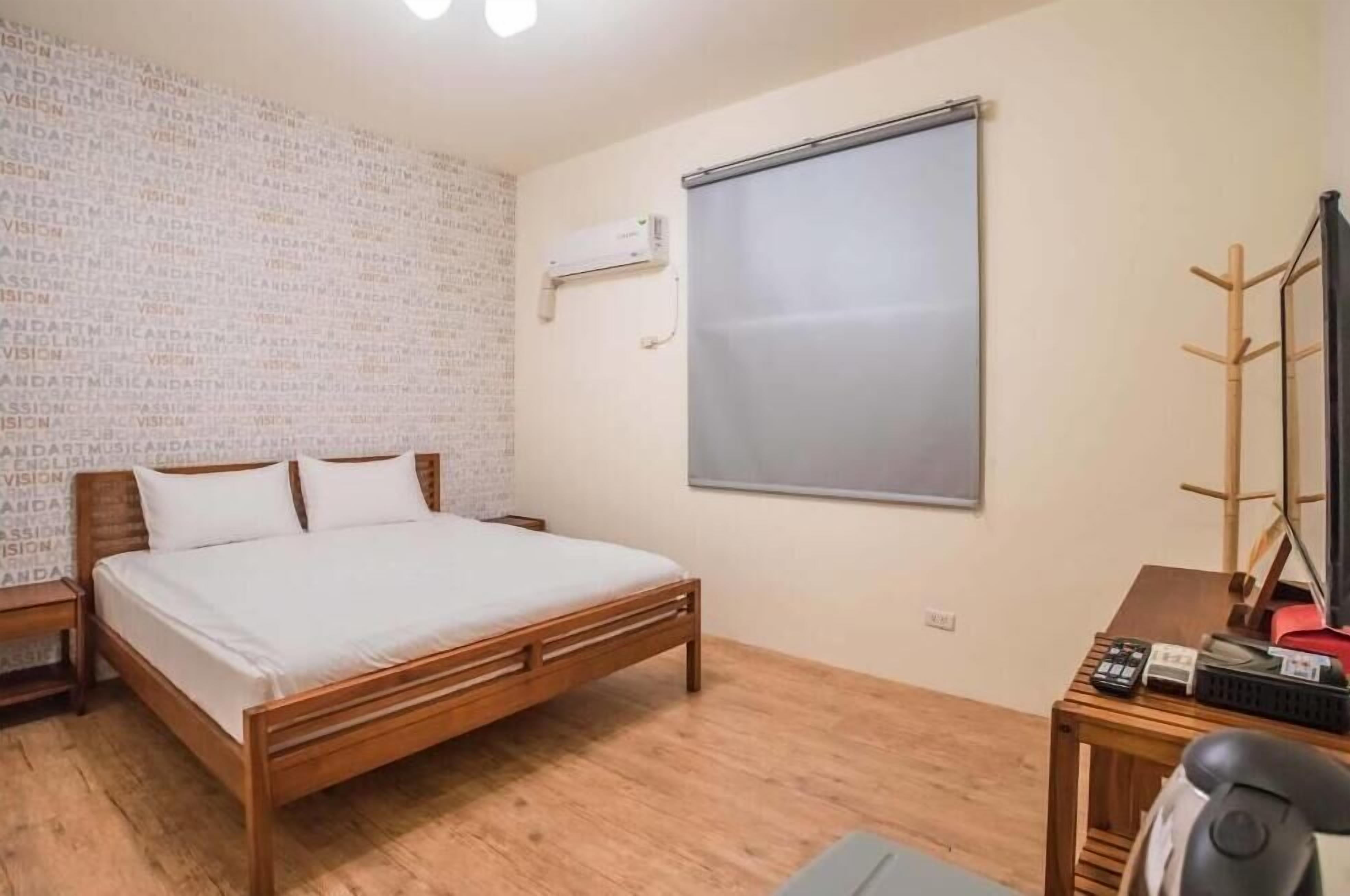 Un dormitorio con una cama de madera, televisor y un escritorio con silla.