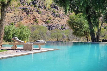Una piscina al aire libre, sillones reclinables de piscina