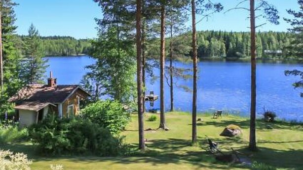 A lakeside cabin with a small deck and a view of the lake.