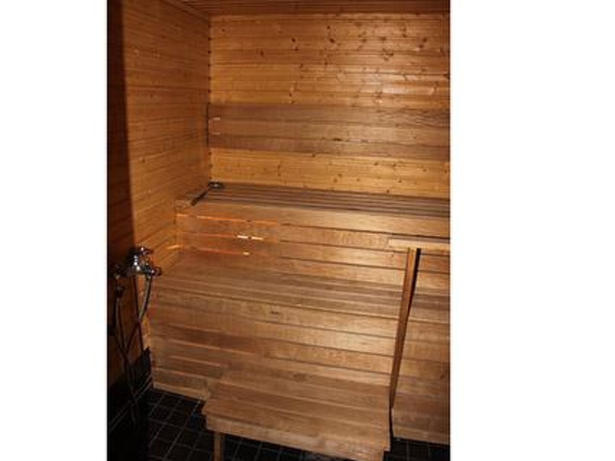 A wooden sauna room with a bench, a bench on the wall, and a metal door.
