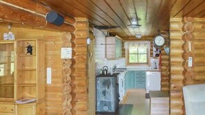 A log cabin interior with a kitchen, wooden cabinets, and a dining area.