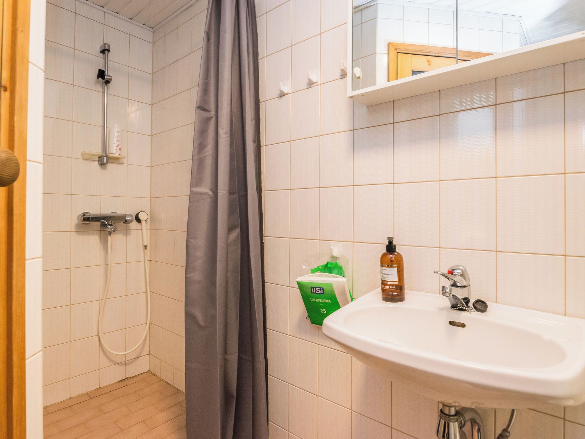 A bathroom with a shower, a sink, and toiletries.