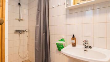 A bathroom with a shower, a sink, and toiletries.