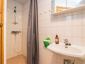 Casa de banho com chuveiro, lavatório e artigos de higiene pessoal.
