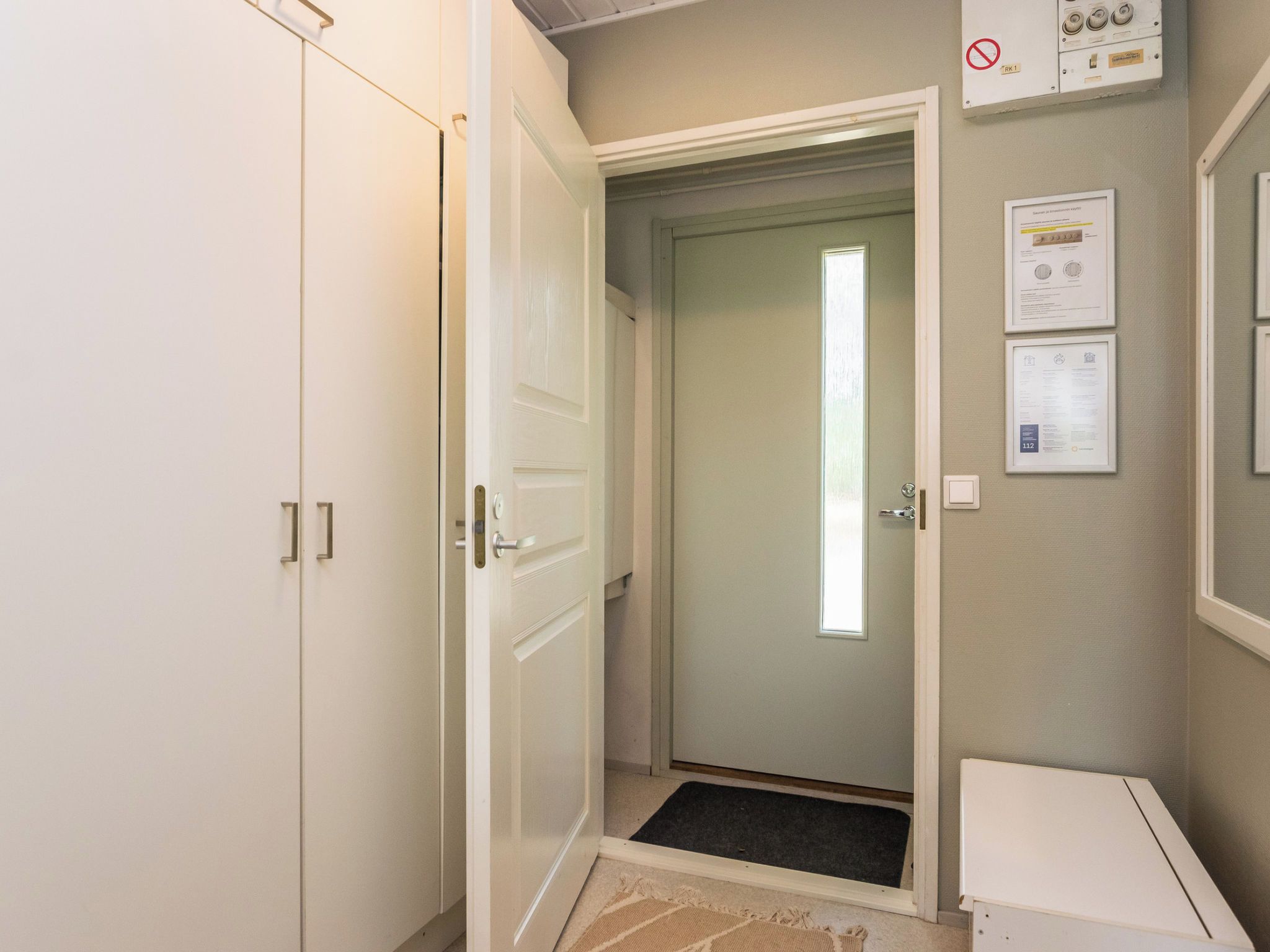 Ein Flur mit einer zur Kammer führenden Tür, einem weißen Schrank und einem an der Wand montierten Thermostat.