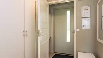 Ein Flur mit einer zur Kammer führenden Tür, einem weißen Schrank und einem an der Wand montierten Thermostat.