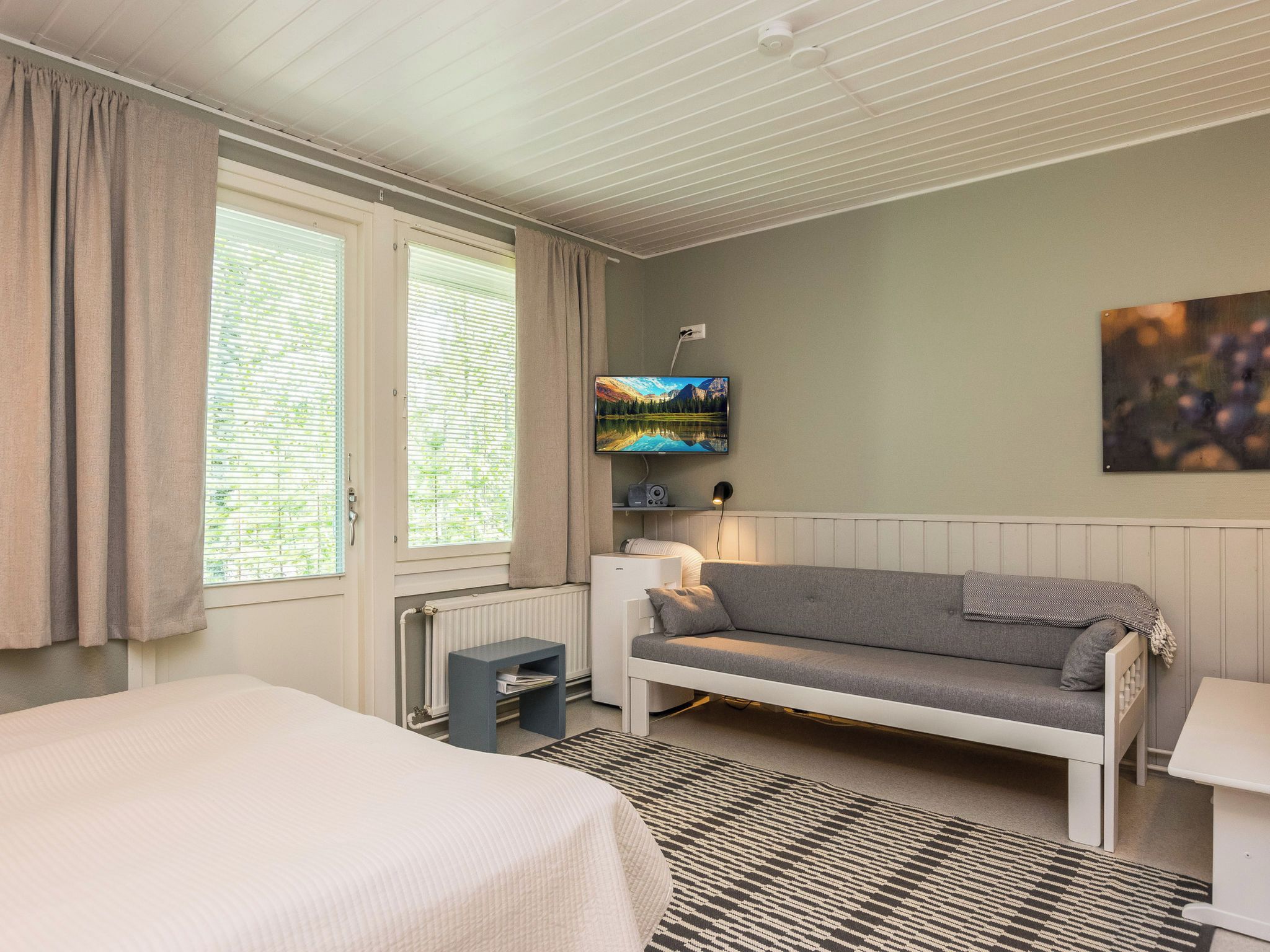 Ein Hotelzimmer mit Bett, einer Couch, einem Fernseher und einer Heizung.
