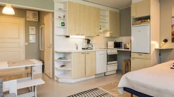 A compact bedroom with a bed, bedside table, and a small desk with a chair.