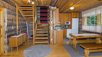 L’intérieur d’un chalet rustique comprend un escalier en bois, un coin cuisine avec un four à micro-ondes et une table à manger.